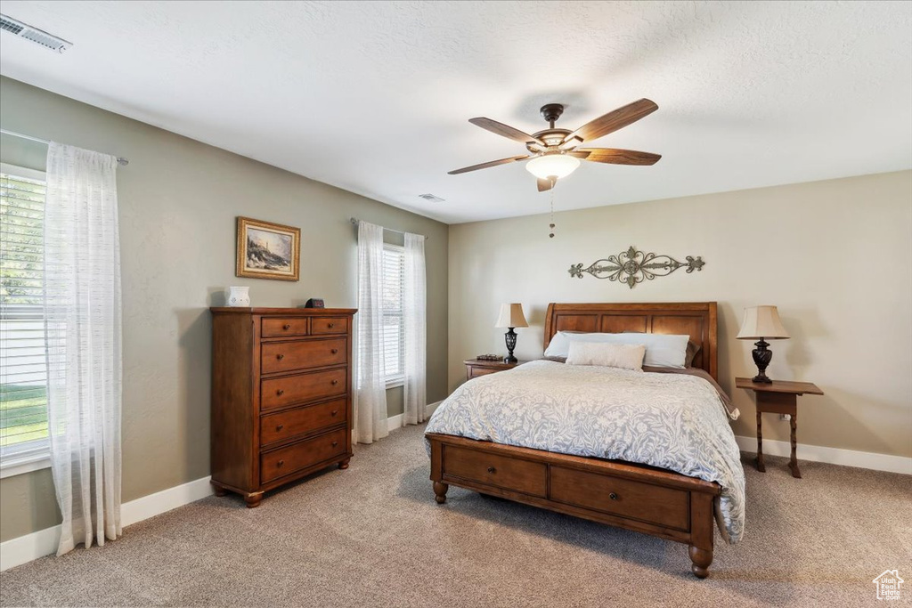 Bedroom with light colored carpet and a ceiling fan