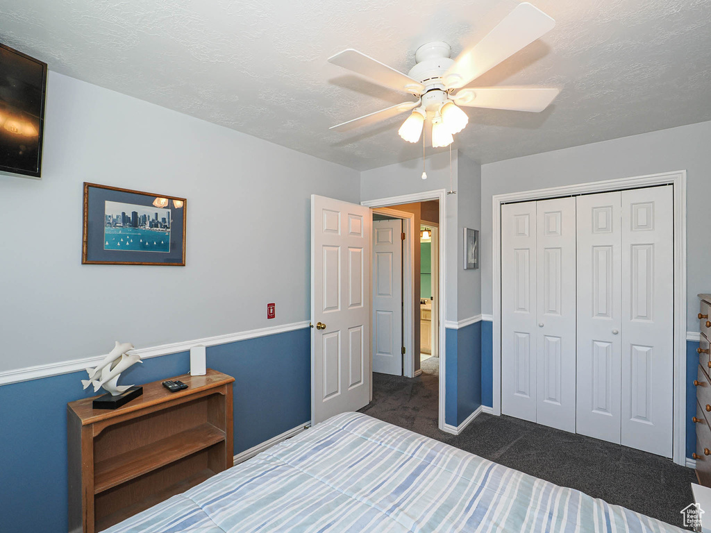 Bedroom featuring dark colored carpet, a closet, and a ceiling fan