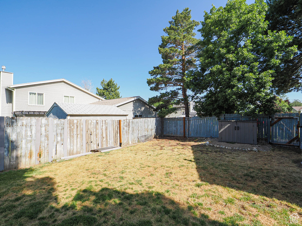 Fenced backyard featuring a storage shed