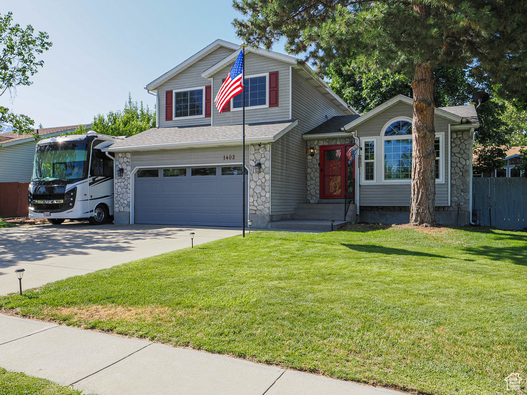 View of front of house with stone siding, driveway, and an attached garage
