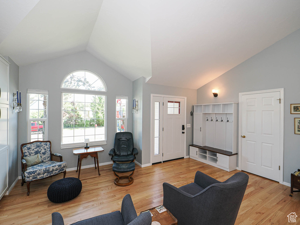 Living area with light wood finished floors, healthy amount of natural light, and high vaulted ceiling