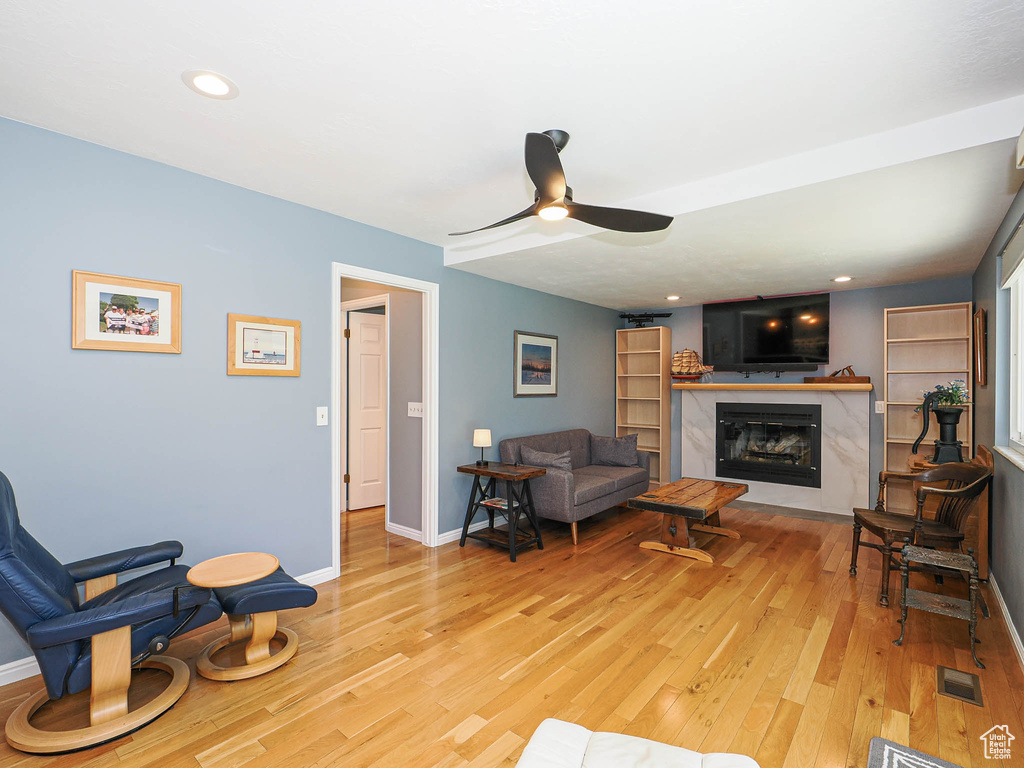 Living room with light wood finished floors, a high end fireplace, a ceiling fan, and recessed lighting
