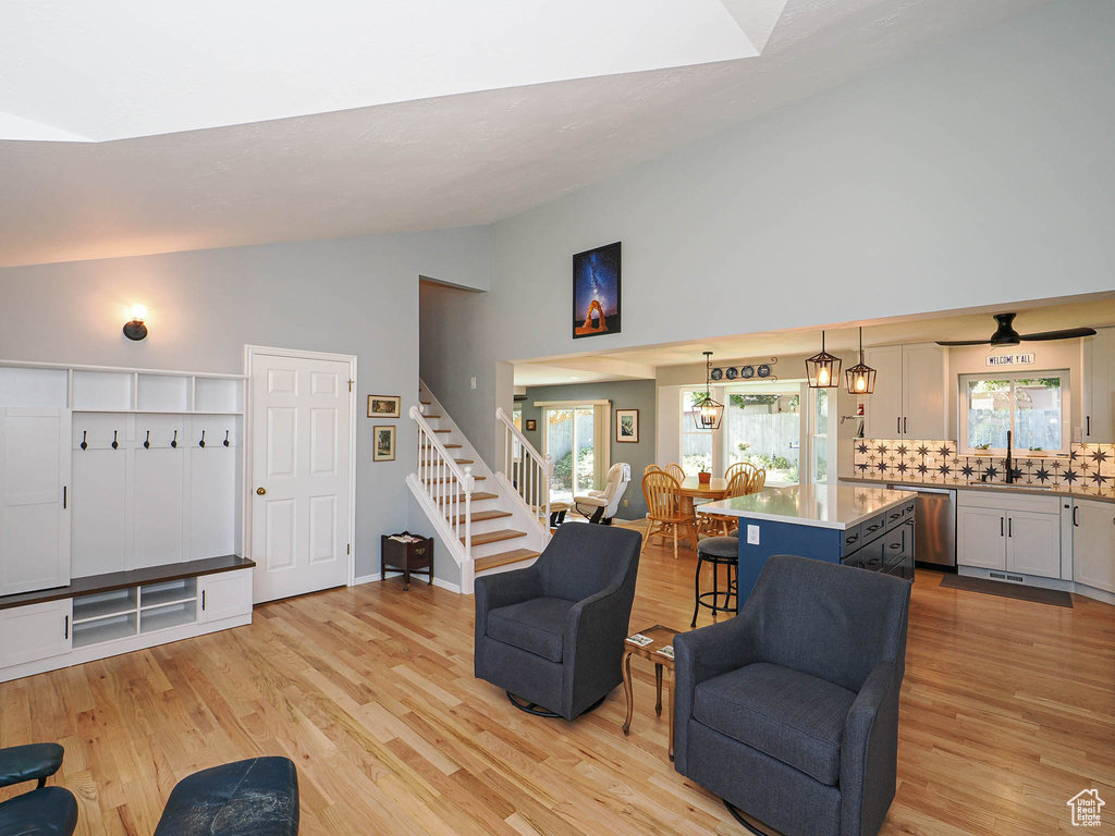 Living area featuring light wood-style flooring, high vaulted ceiling, and stairway