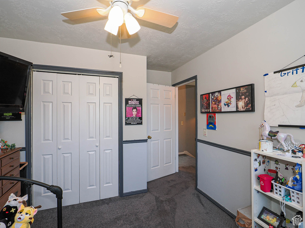Bedroom featuring dark colored carpet, a textured ceiling, a closet, and ceiling fan