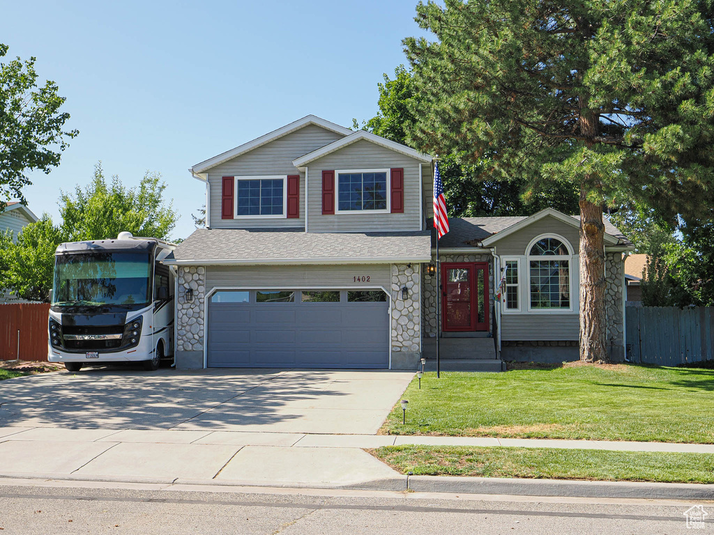 Traditional-style home featuring a garage, driveway, a shingled roof, and stone siding