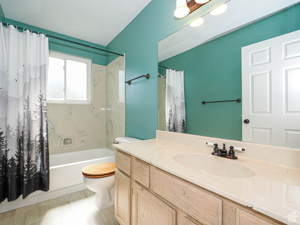 Bathroom with vanity, shower / tub combo with curtain, and wood finished floors
