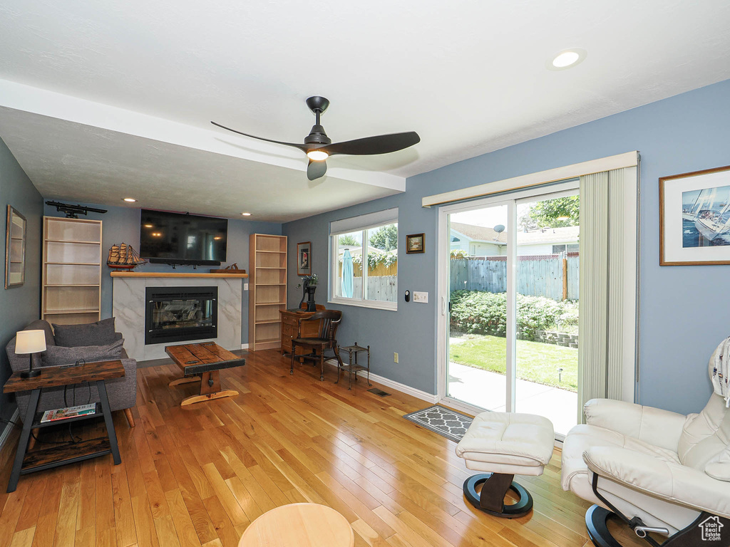 Living area with hardwood / wood-style floors, a premium fireplace, a ceiling fan, and recessed lighting
