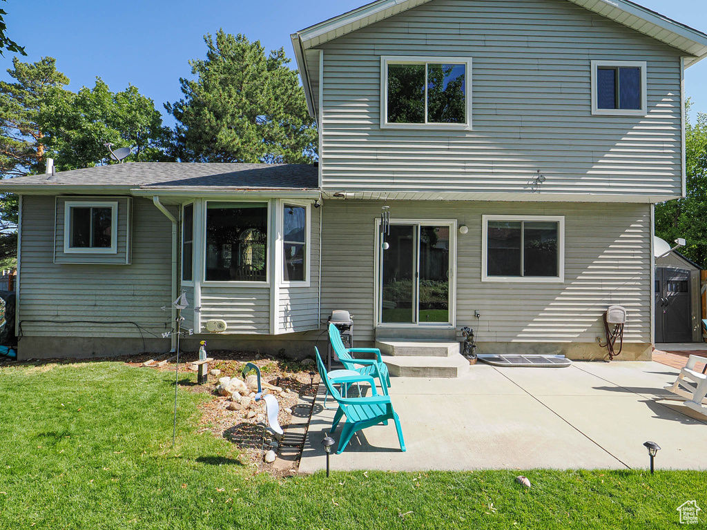 Back of property featuring entry steps, a yard, and a patio