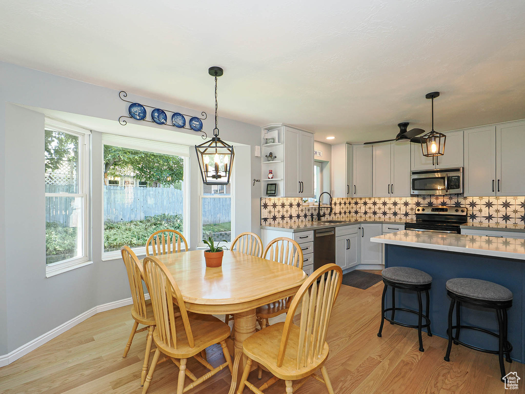 Dining area featuring light wood-style flooring, a chandelier, and a ceiling fan