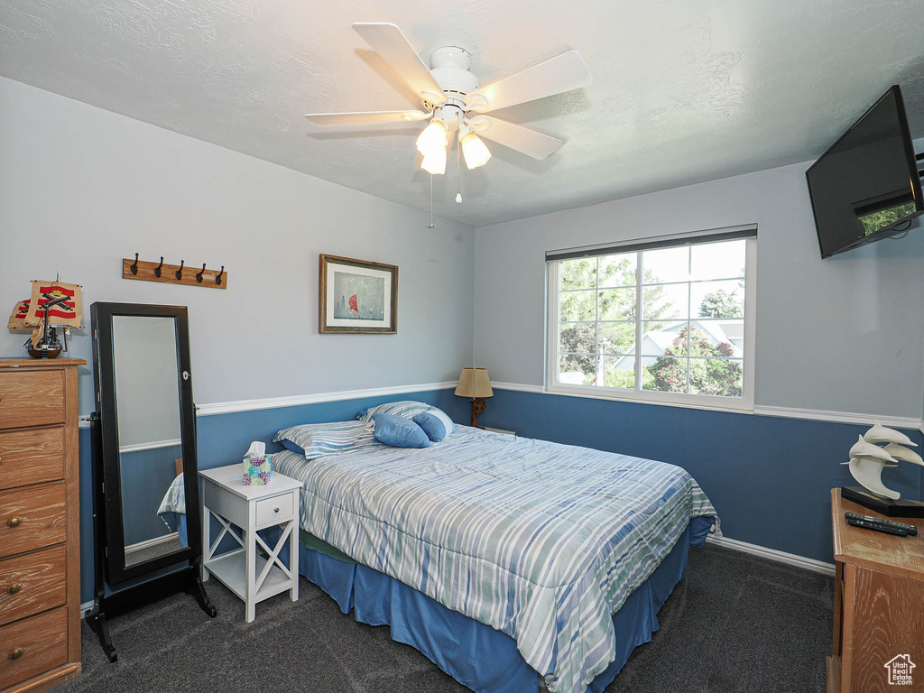 Carpeted bedroom featuring ceiling fan and baseboards