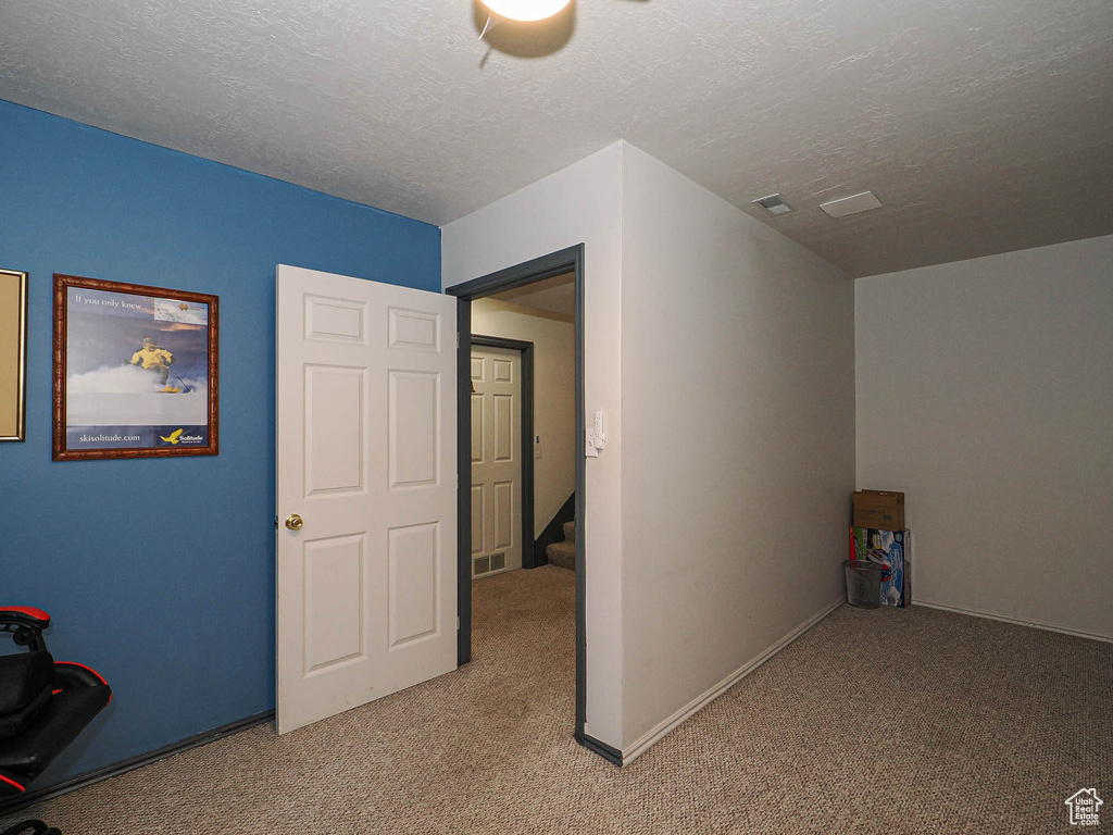 Additional living space with light colored carpet, a textured ceiling, and stairs