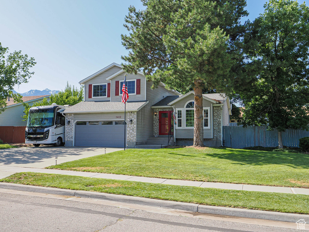 View of front facade featuring an attached garage, stone siding, and concrete driveway