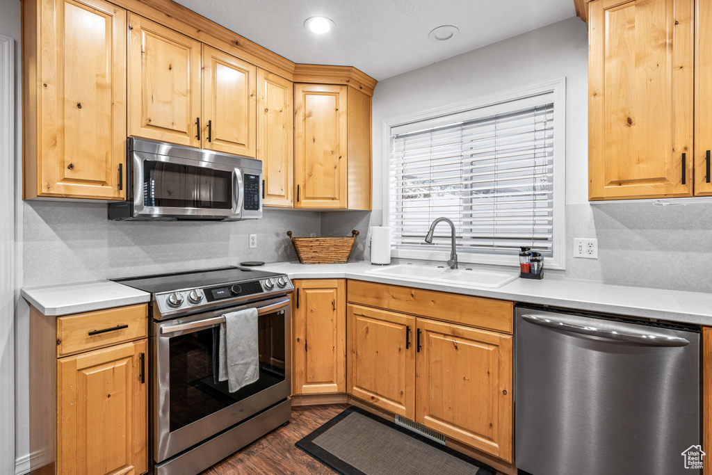 Kitchen with appliances with stainless steel finishes, light countertops, dark wood-type flooring, backsplash, and recessed lighting