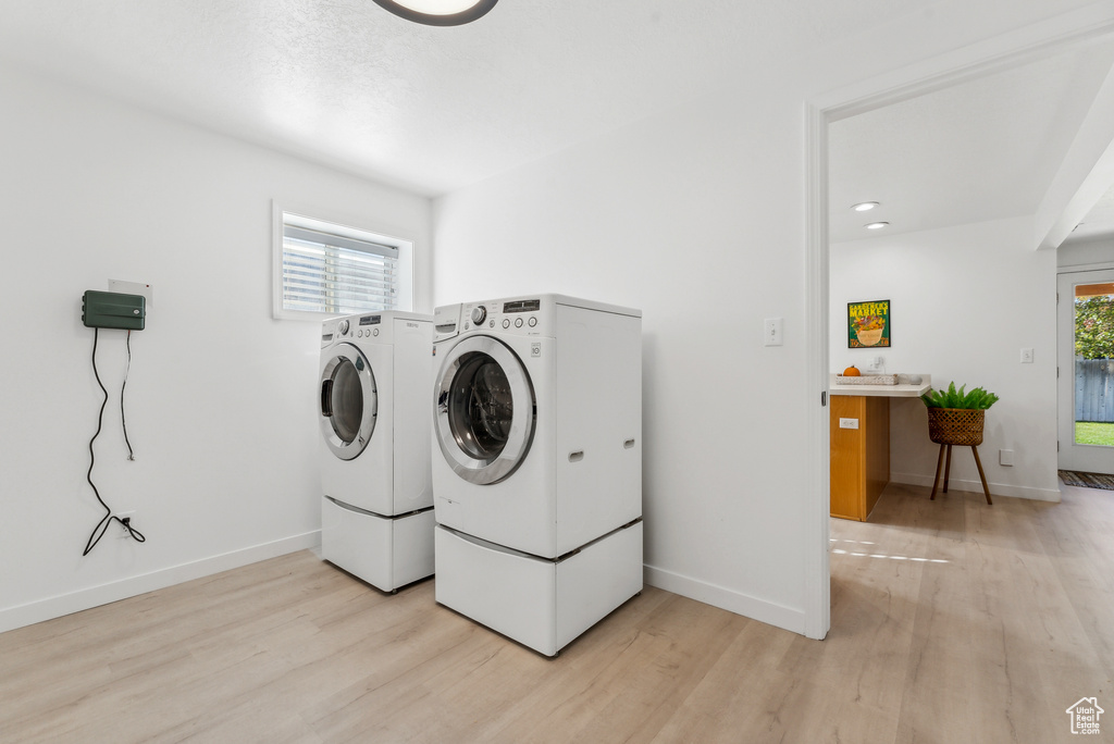 Laundry room with washer and dryer and light wood-type flooring