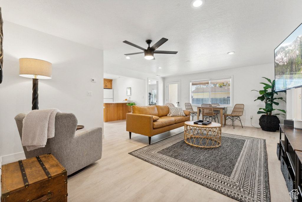 Living room with light wood-style floors, ceiling fan, and recessed lighting