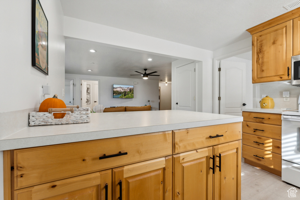 Kitchen with stove, light countertops, recessed lighting, stainless steel microwave, and ceiling fan