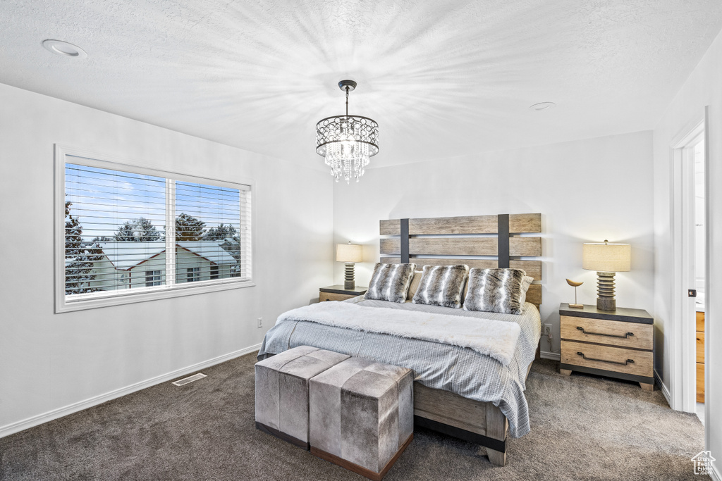 Bedroom featuring carpet, a chandelier, and a textured ceiling
