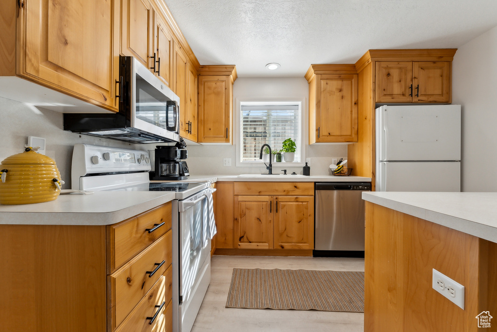 Kitchen with appliances with stainless steel finishes, light countertops, and a textured ceiling