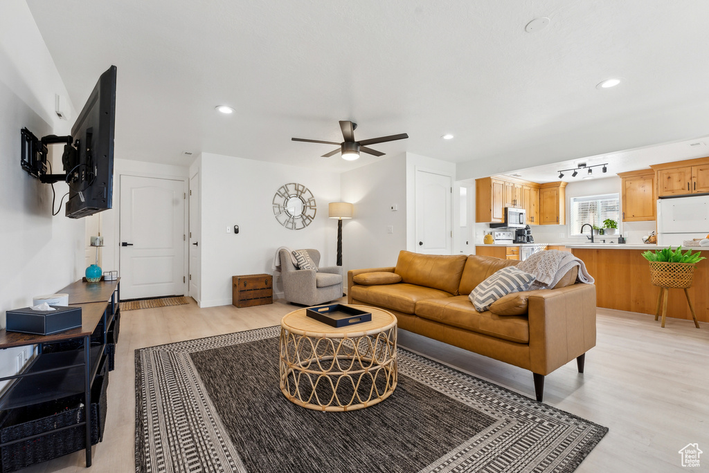 Living area featuring light wood-style floors, ceiling fan, and recessed lighting