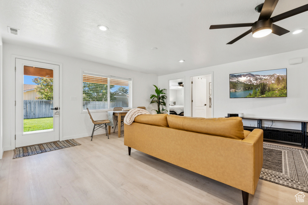 Living room with light wood-style flooring, ceiling fan, and recessed lighting
