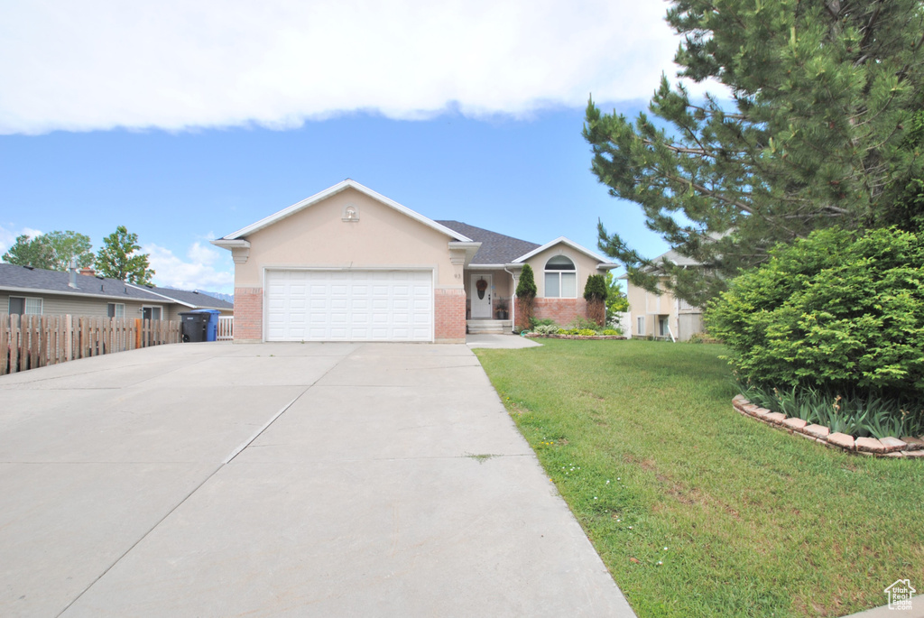 Single story home featuring a garage, driveway, brick siding, and stucco siding