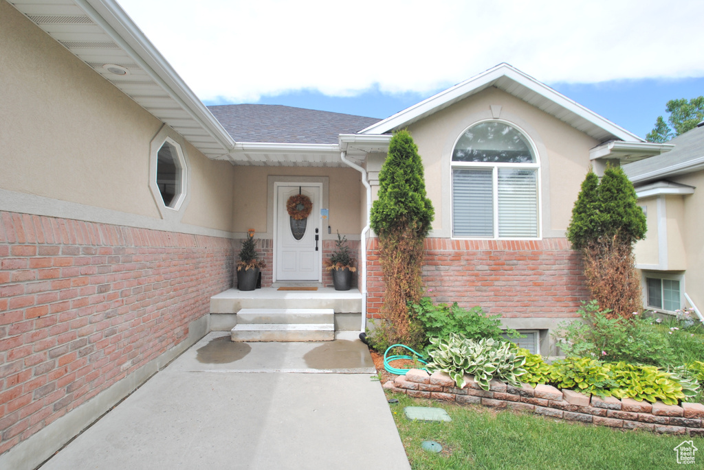 Property entrance featuring stucco siding, brick siding, and roof with shingles