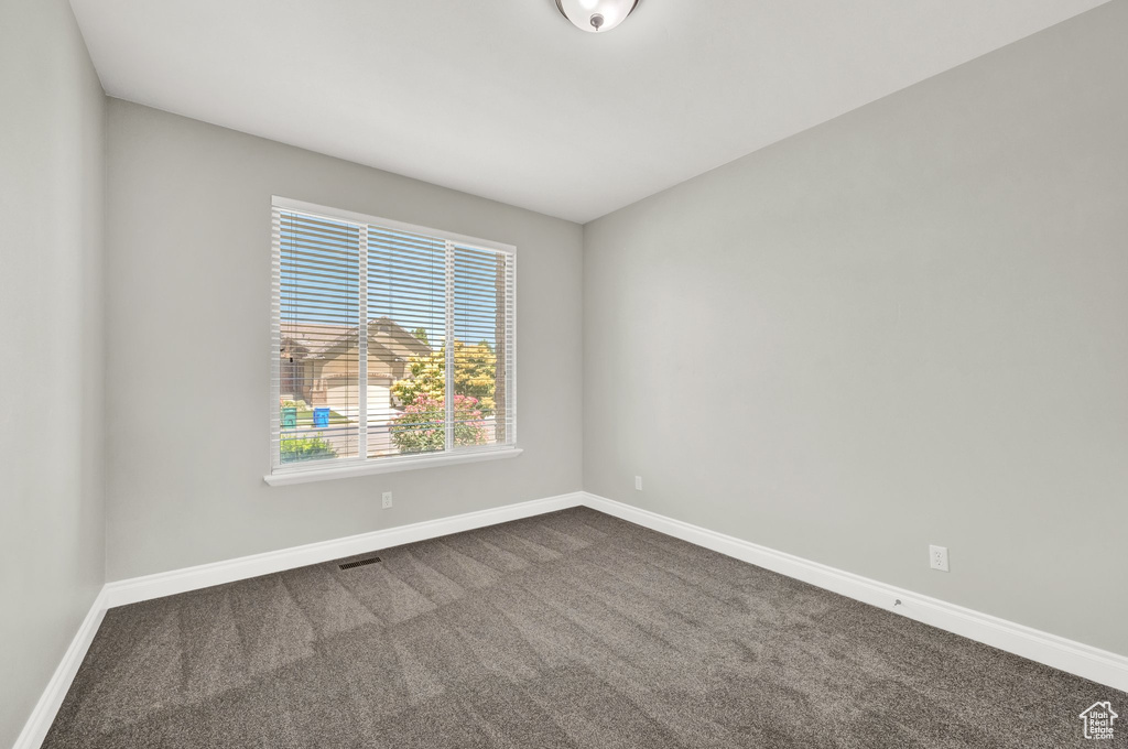 Empty room featuring dark colored carpet and baseboards