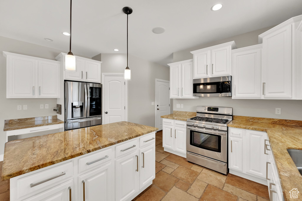 Kitchen featuring stainless steel appliances, recessed lighting, stone tile flooring, white cabinetry, and pendant lighting