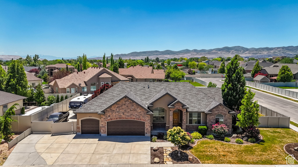 View of front of house with an attached garage, driveway, a residential view, and a mountain view