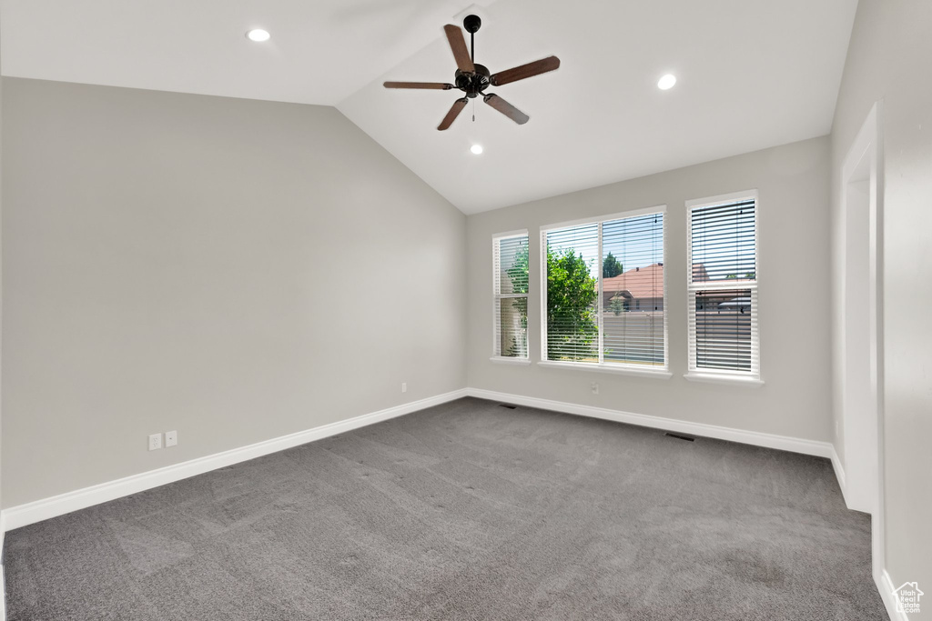 Empty room featuring a ceiling fan, vaulted ceiling, dark colored carpet, and recessed lighting