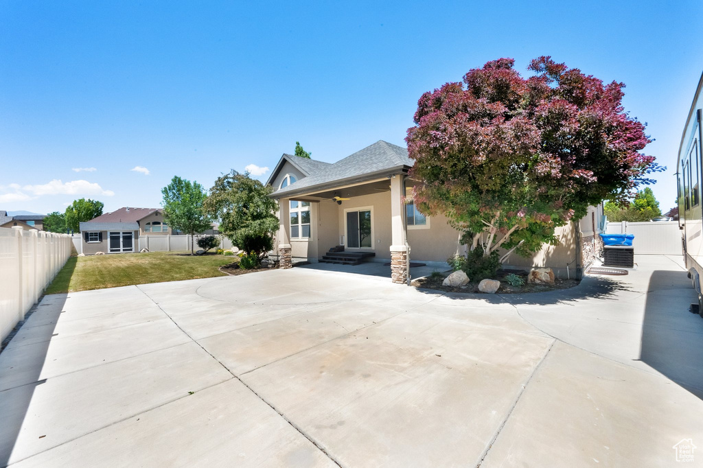 View of front of property featuring stucco siding, a fenced backyard, ceiling fan, and a shingled roof