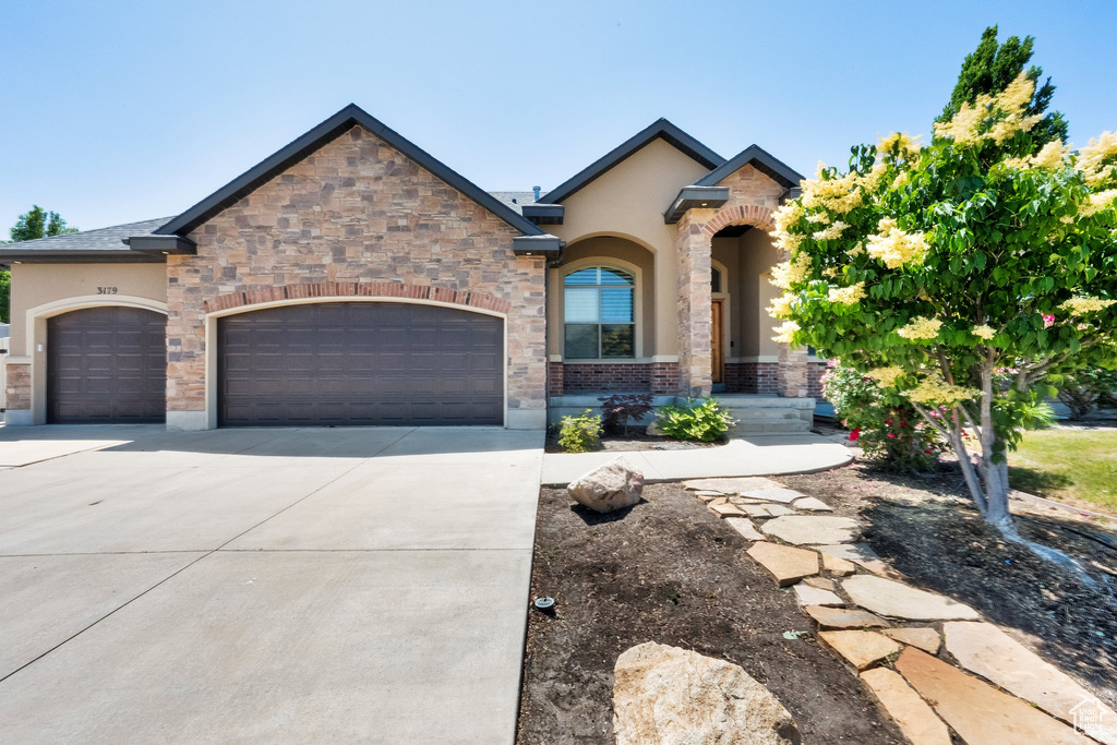 View of front of home featuring a garage, concrete driveway, and stucco siding