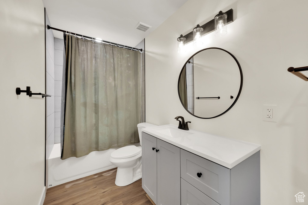 Full bathroom featuring vanity, shower / bath combination with curtain, and wood finished floors