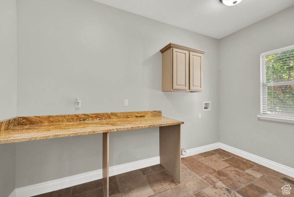 Washroom featuring washer hookup, cabinet space, stone tile flooring, and an office area