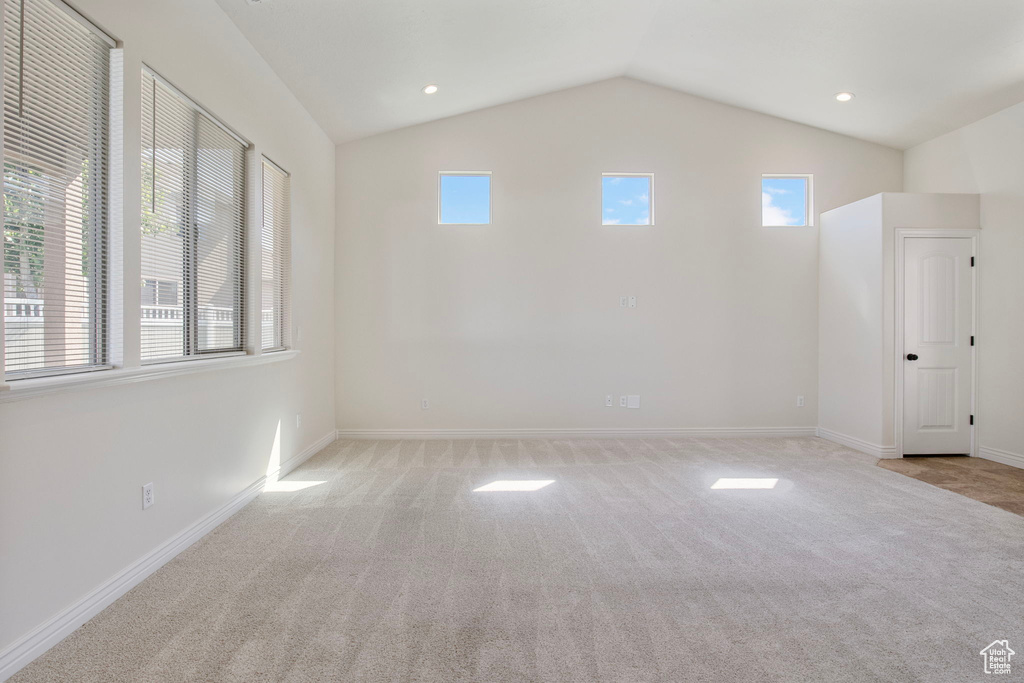 Carpeted spare room with healthy amount of natural light, vaulted ceiling, and recessed lighting