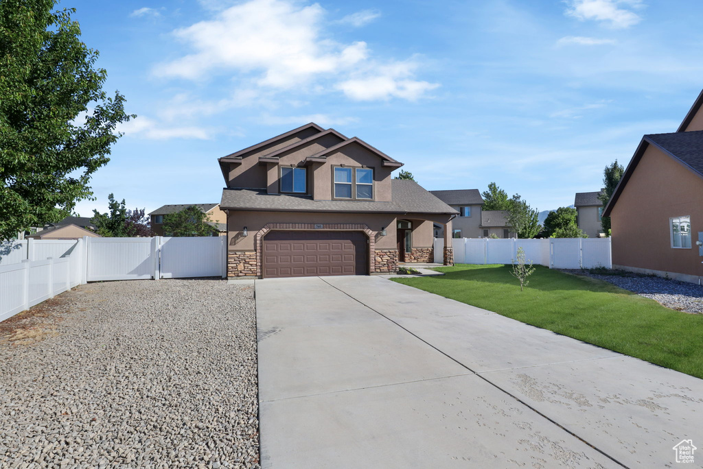 Craftsman house featuring driveway, stone siding, stucco siding, a gate, and a garage