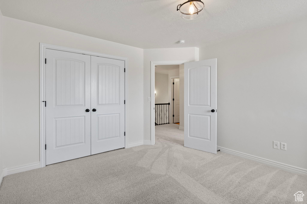Unfurnished bedroom featuring light carpet and a closet