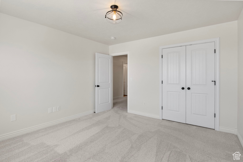 Unfurnished bedroom with light colored carpet and a closet