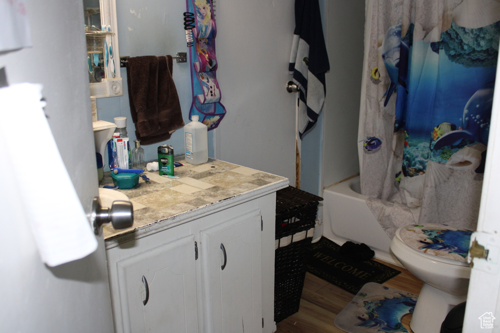 Full bathroom with vanity, wood finished floors, and shower / bath combination with curtain