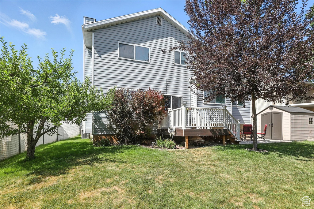Back of property featuring a storage shed, a wooden deck, and a chimney