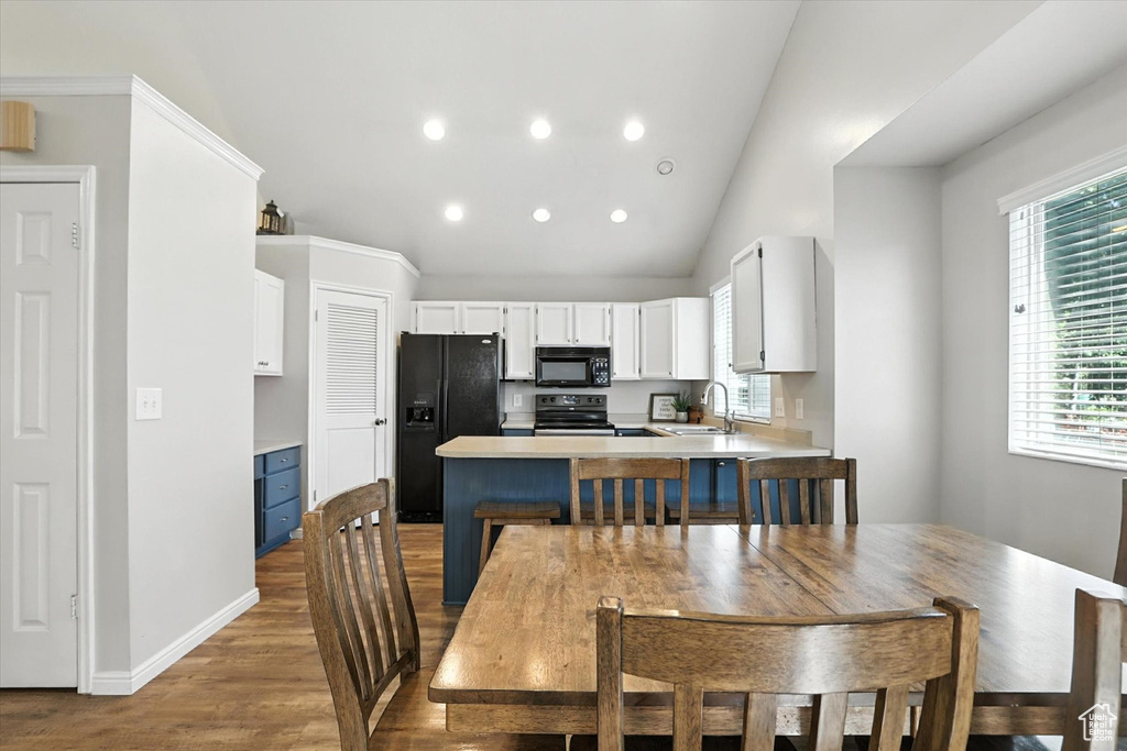 Dining room with wood finished floors, vaulted ceiling, and recessed lighting