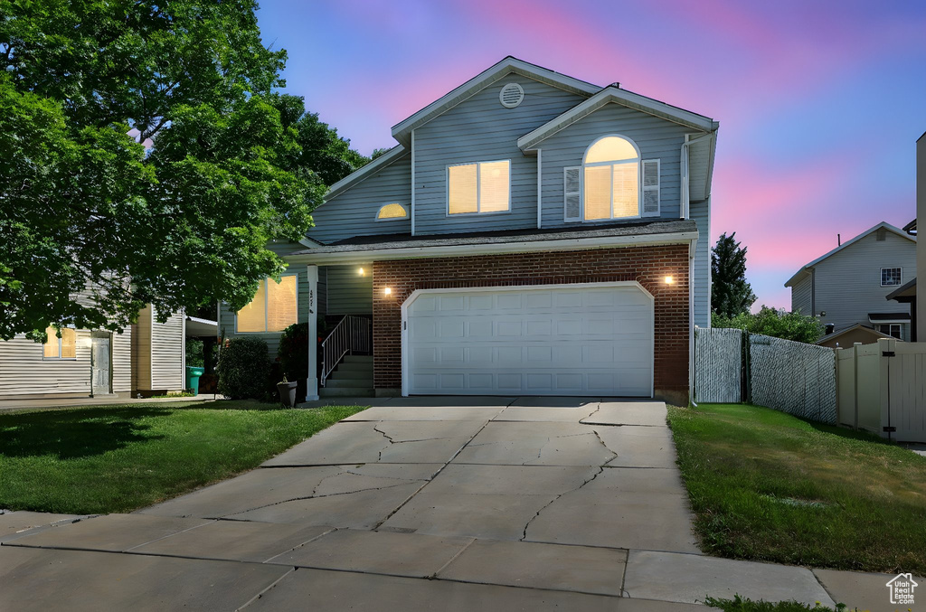Traditional-style home featuring a garage, concrete driveway, and brick siding