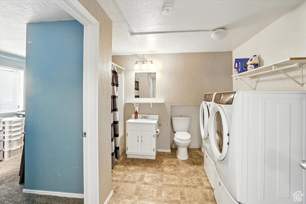 Full bathroom featuring washing machine and clothes dryer, a shower with shower curtain, vanity, a textured wall, and a textured ceiling