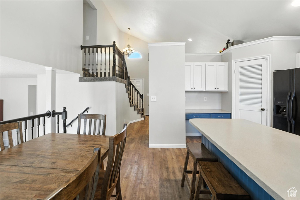 Dining space with a chandelier, dark wood-style flooring, stairway, recessed lighting, and high vaulted ceiling