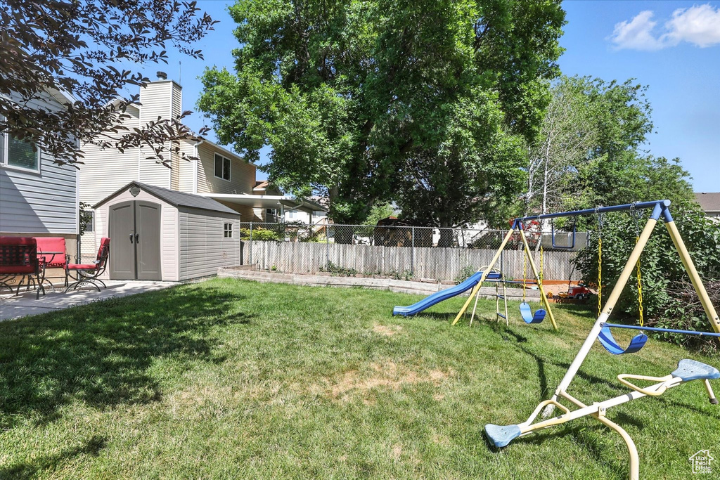 Fenced backyard with a playground, a storage shed, and a patio