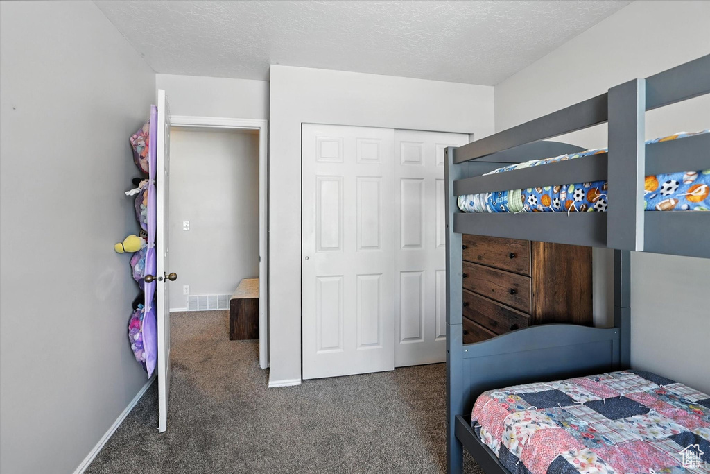 Bedroom featuring carpet flooring, a closet, and a textured ceiling