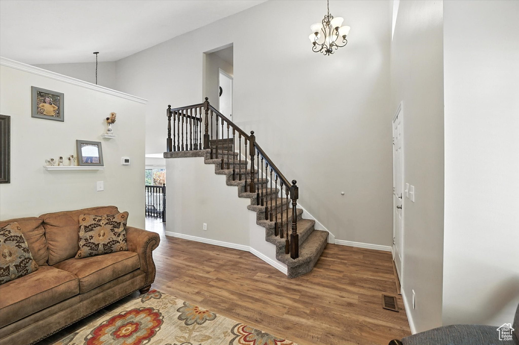 Living area with wood finished floors, a chandelier, stairway, and high vaulted ceiling