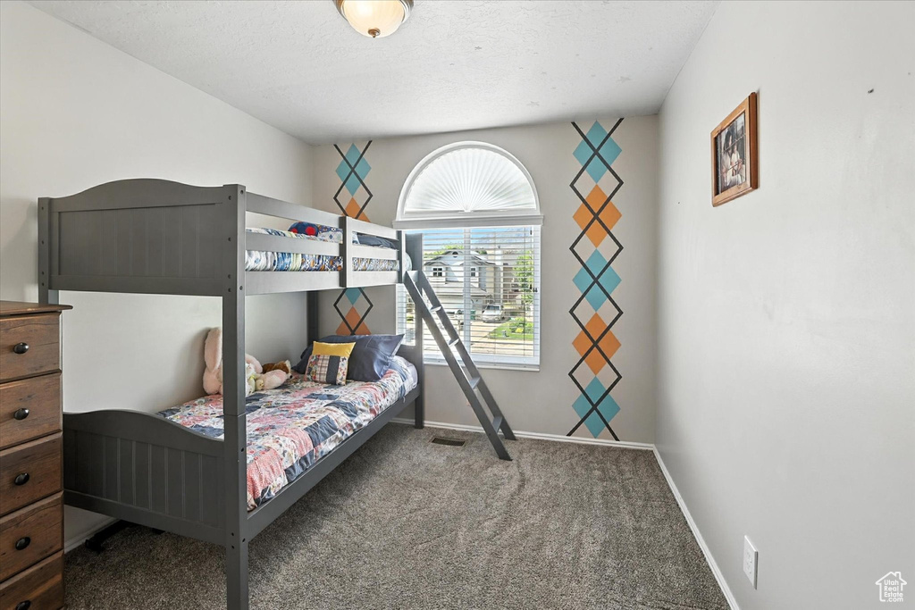 Carpeted bedroom featuring baseboards and a textured ceiling