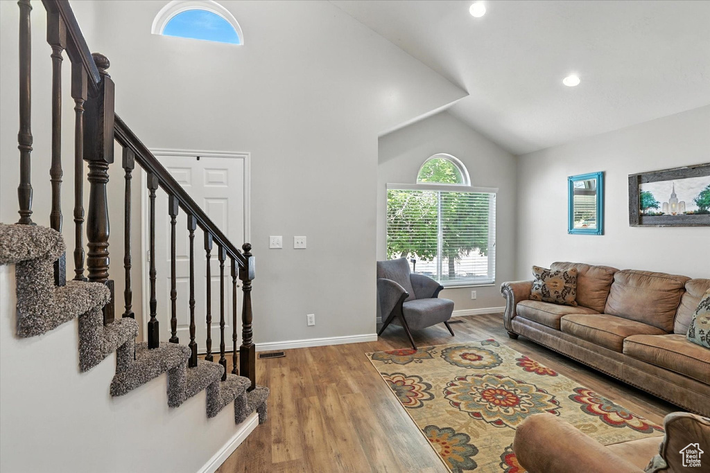 Living area featuring lofted ceiling, wood finished floors, stairway, and recessed lighting