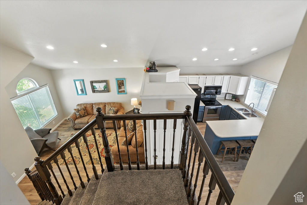 Stairs with healthy amount of natural light, recessed lighting, and wood finished floors